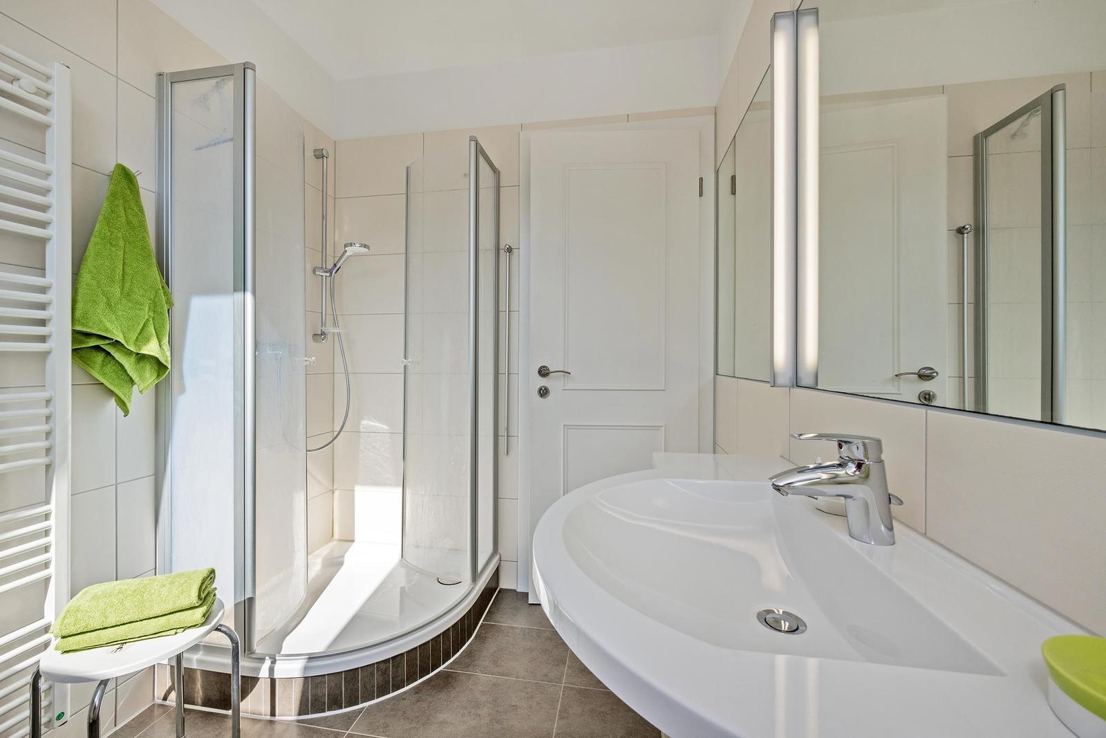 Badezimmer mit Dusche, Waschbecken und Spiegel.