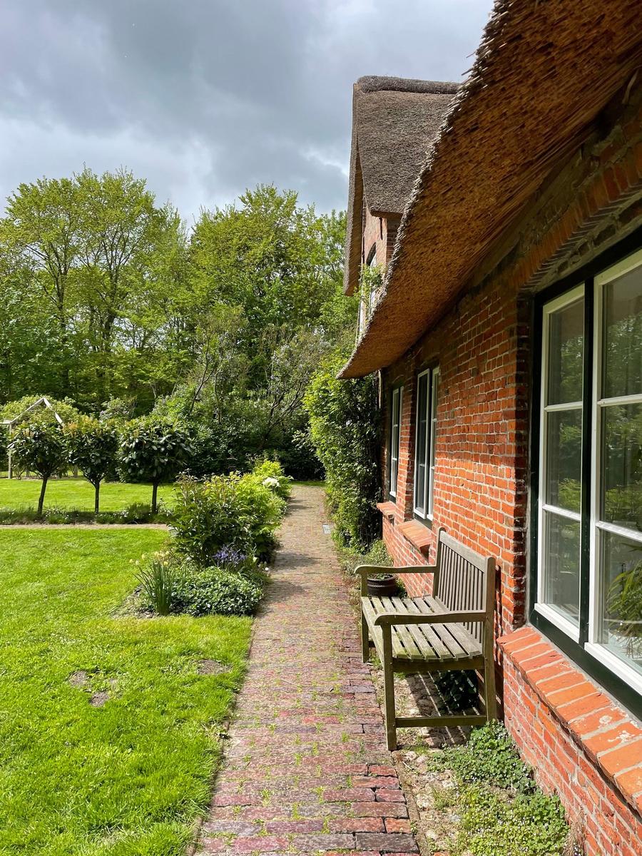Grüner Garten mit Sonnenliegen und Pavillon unter Bäumen.