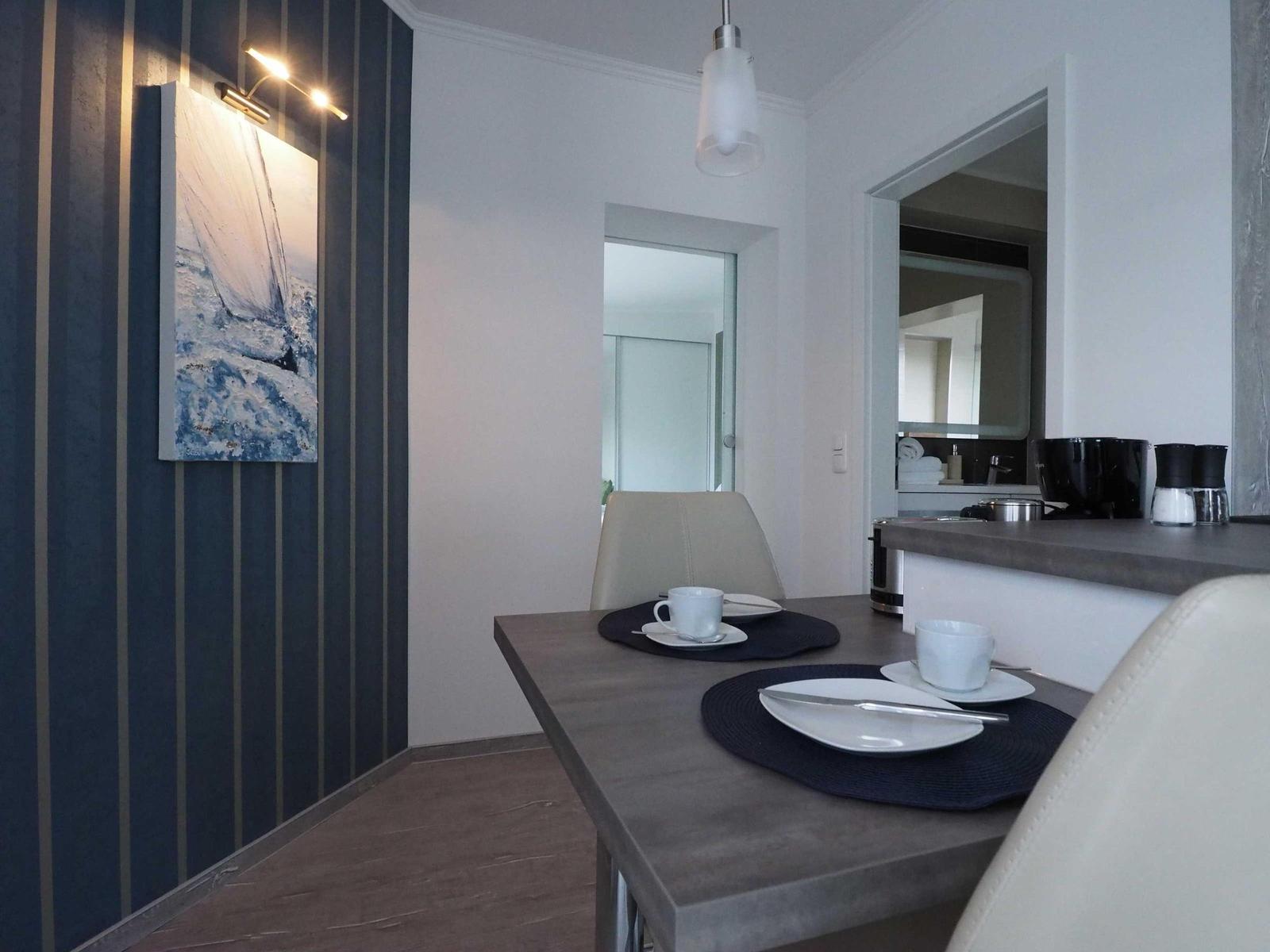 Wohnzimmer mit Sofa, Couchtisch und TV. Wand mit Streifen, Fenster mit Blick.
