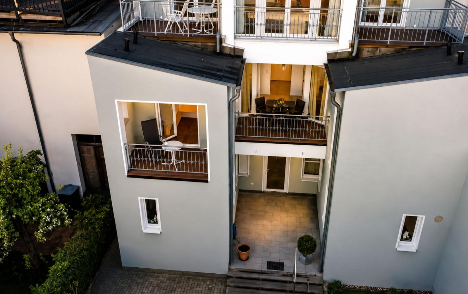 Balkon mit Stuhl und Tulpenblick auf gepflasterten Weg und Grünflächen