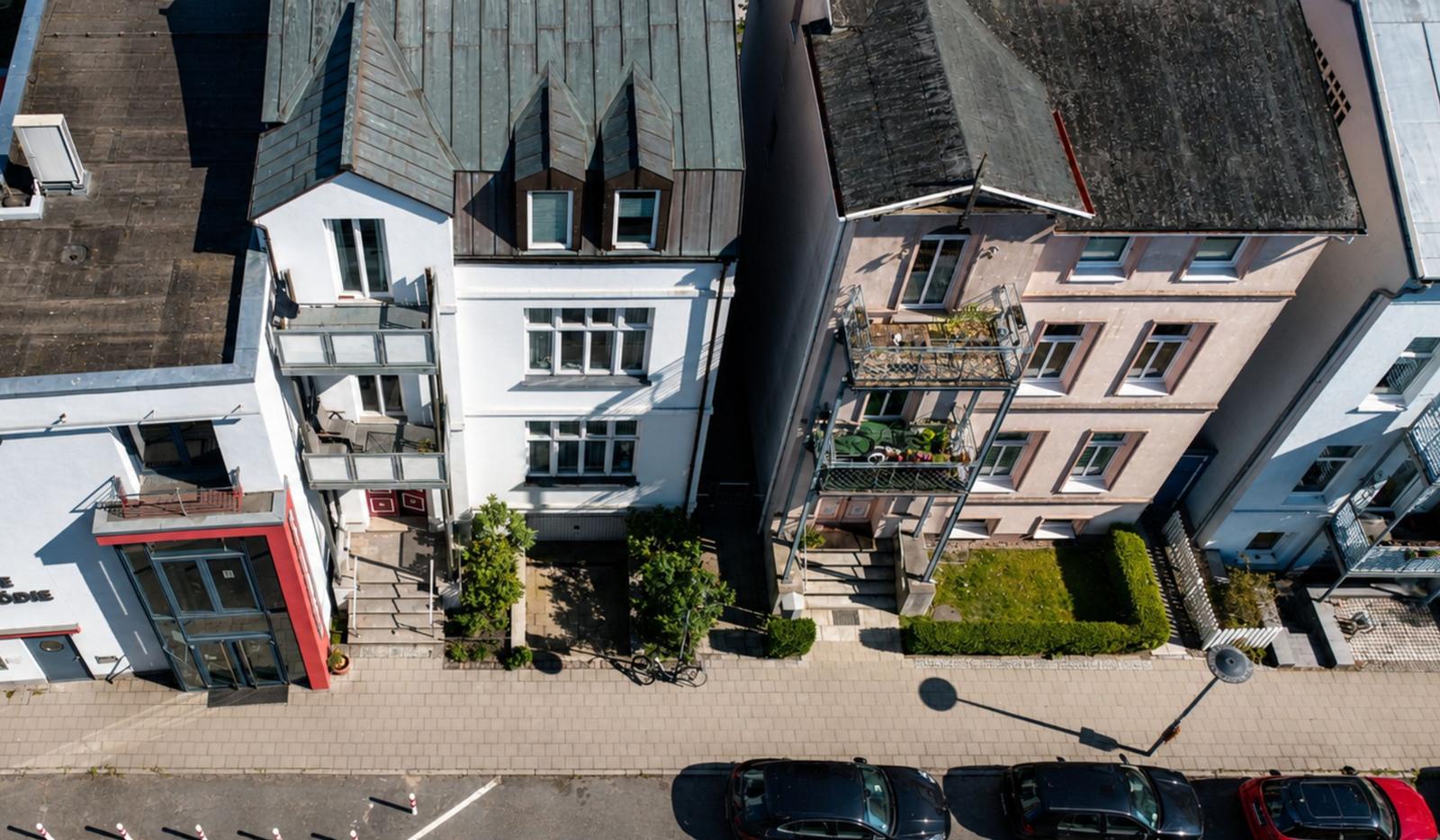 Haus mit Eingangstür, Balkonen und Fenstern. Nummer 9. Vor dem Haus steht ein Baum.