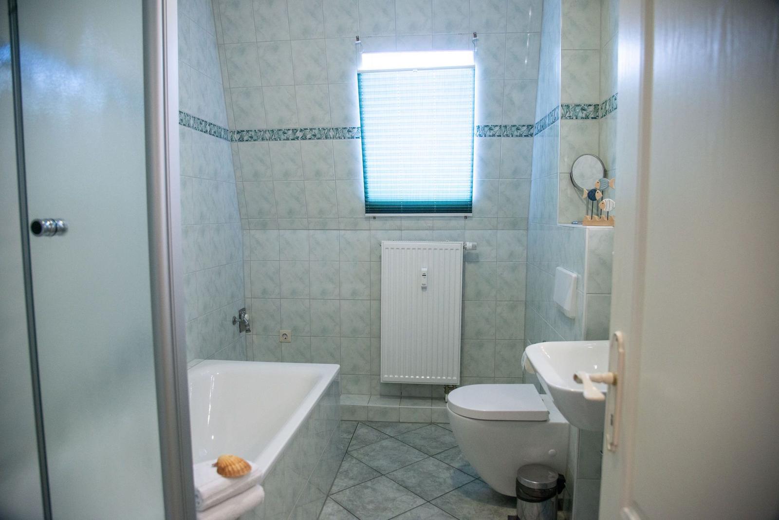 Schlafzimmer mit Bett, TV und Balkon. Dunkelblaue Vorhänge und Wandbilder.