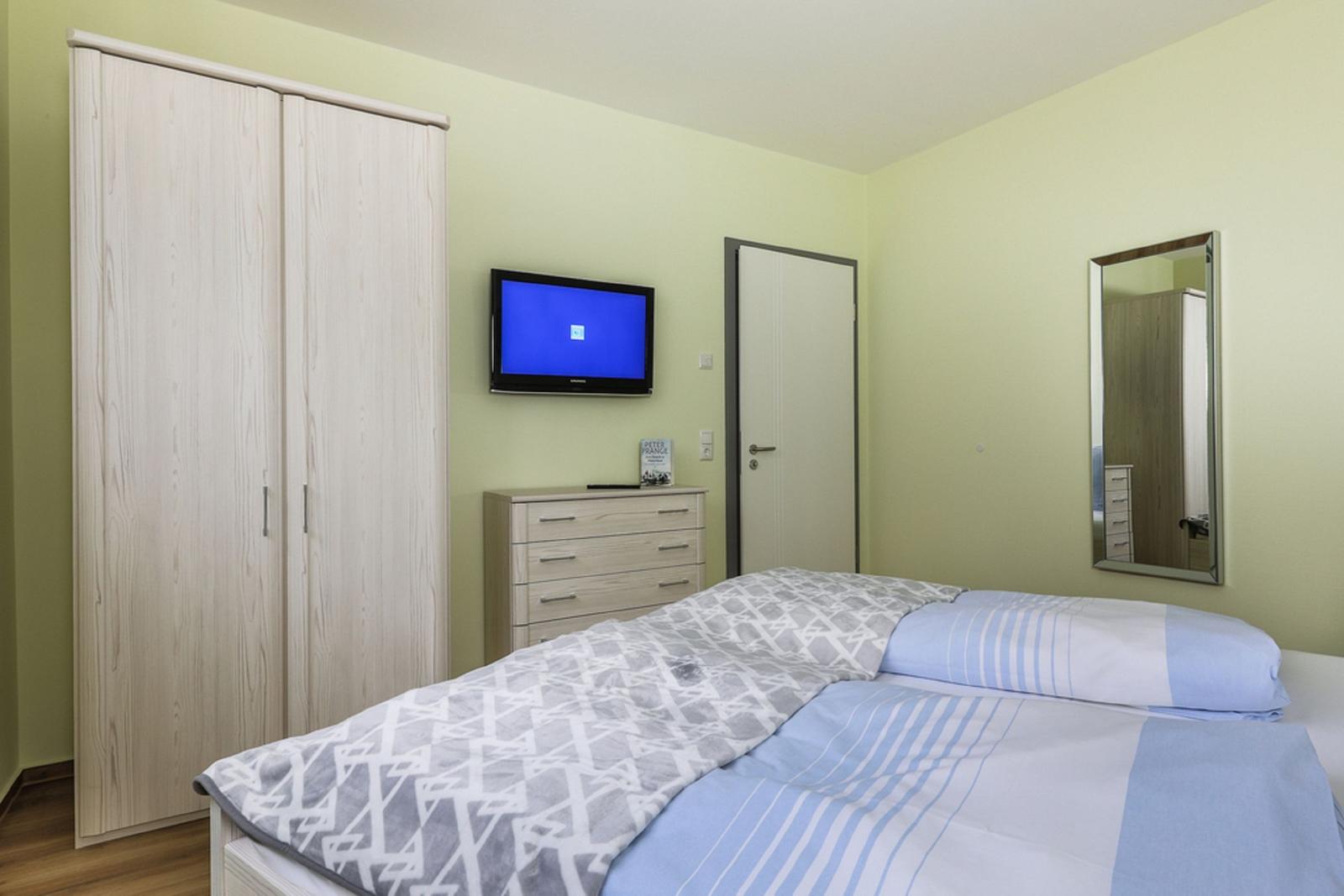 Ein Bett mit gestreifter Bettwäsche und einem Sternenbezug. An den Wänden hängen farbige Bilder.