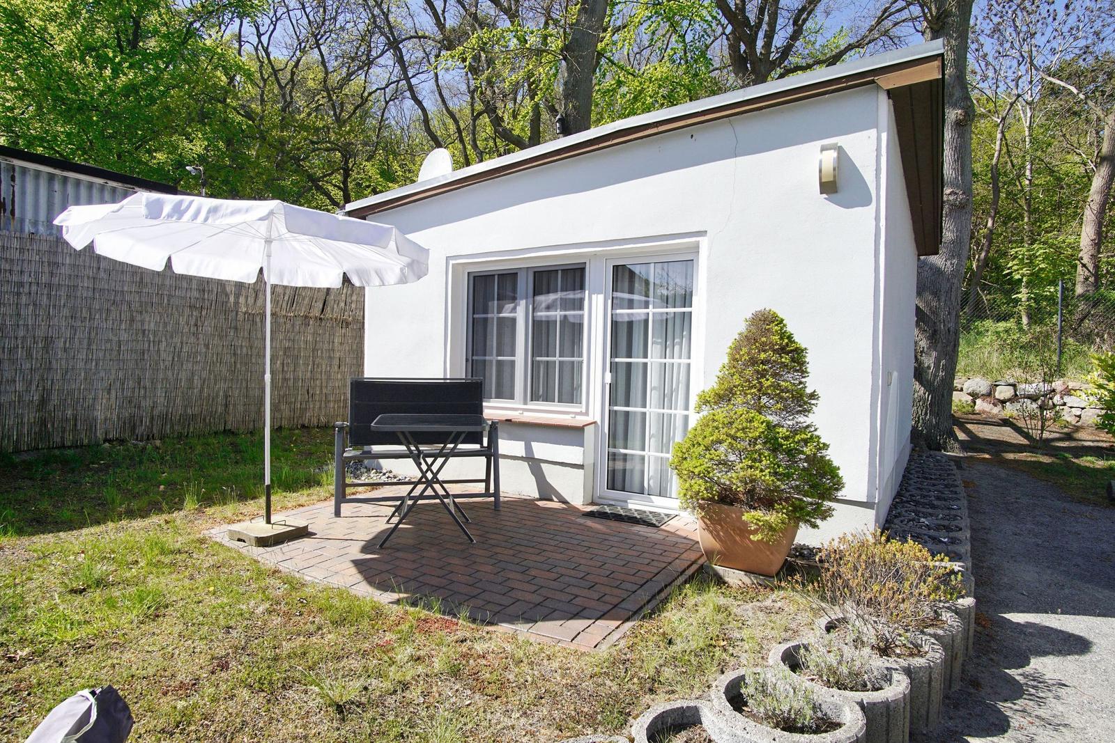 Zimmer mit Doppelbett, Schreibtisch, Tisch mit zwei Stühlen und TV. Große Fenster mit Vorhängen.