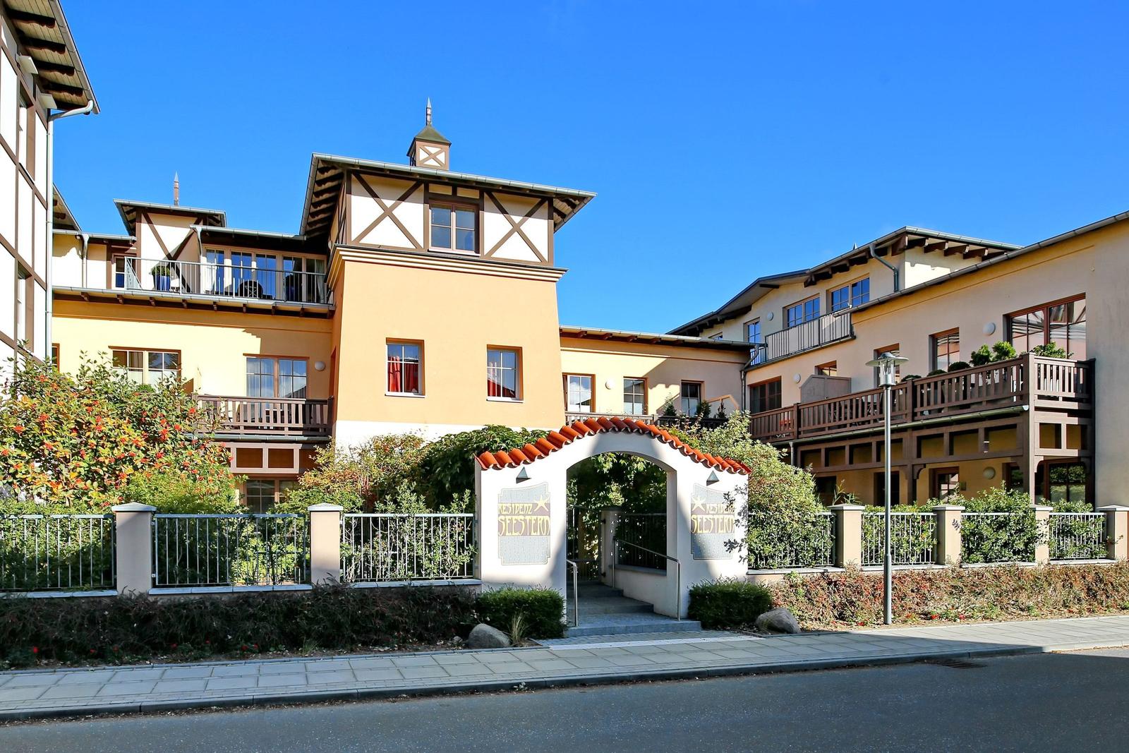 Ferienhaus mit Eingangstore und Balkonen unter blauem Himmel.