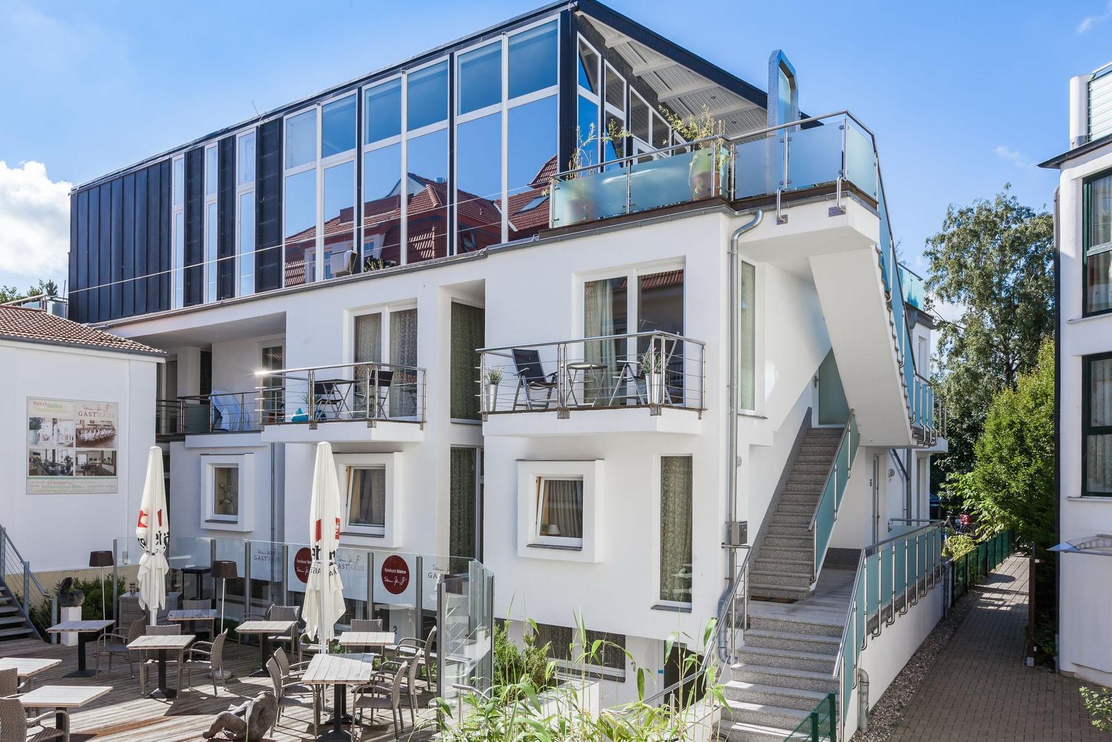 Moderne Wohnanlage mit Balkonen und Terrasse. Außenbereich mit Tischen und Stühlen.