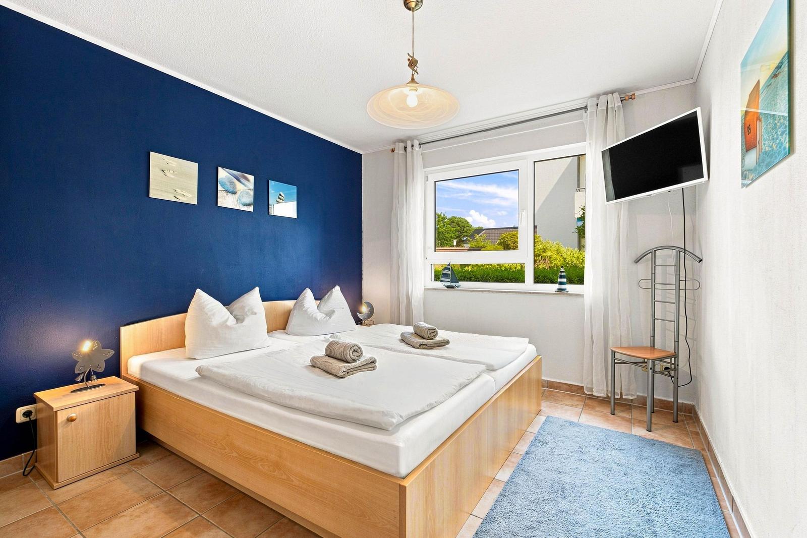 Schlafzimmer mit Doppelbett, Kleiderschrank und TV