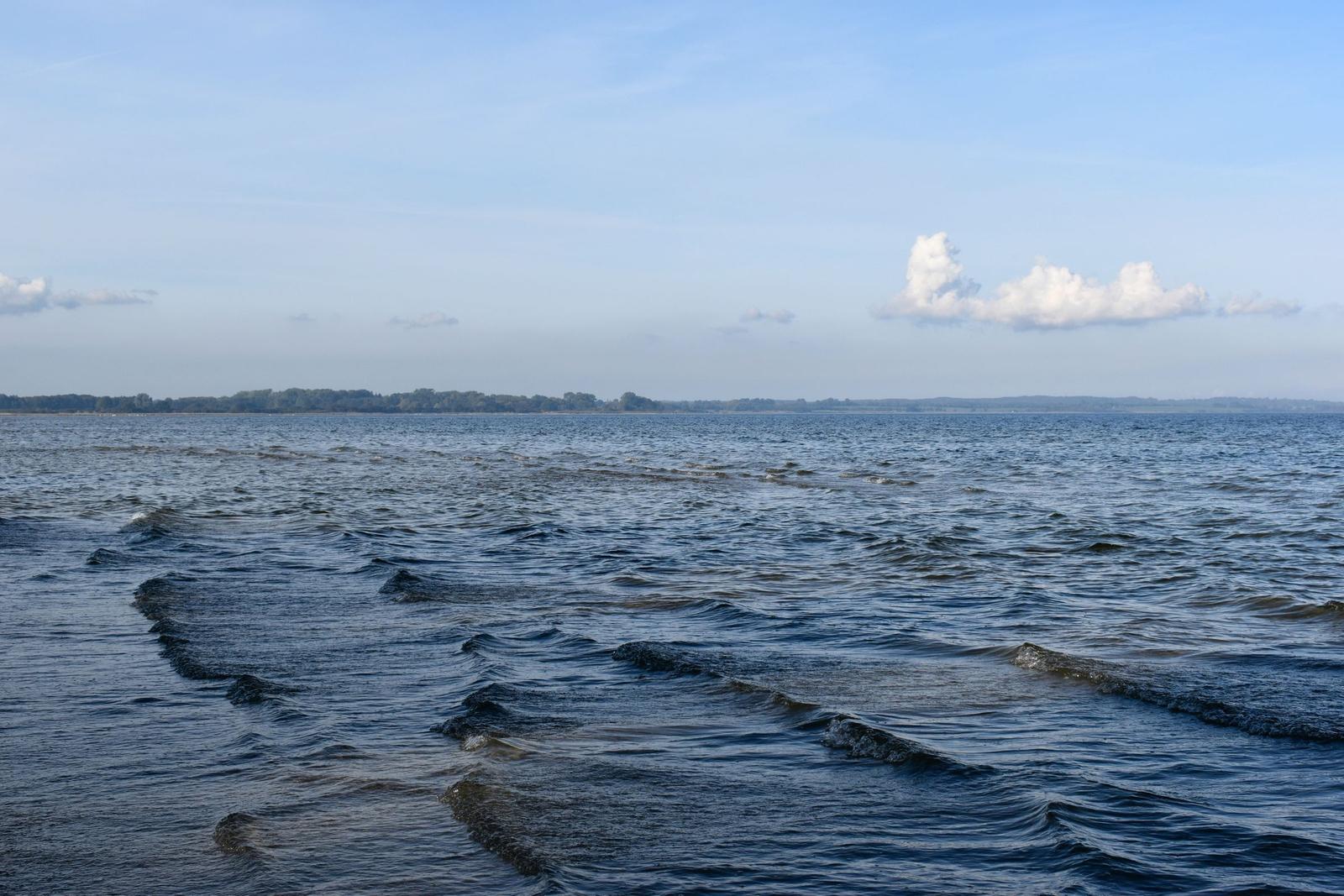 Strand mit Felsen und ruhigem Meer unter blauem Himmel