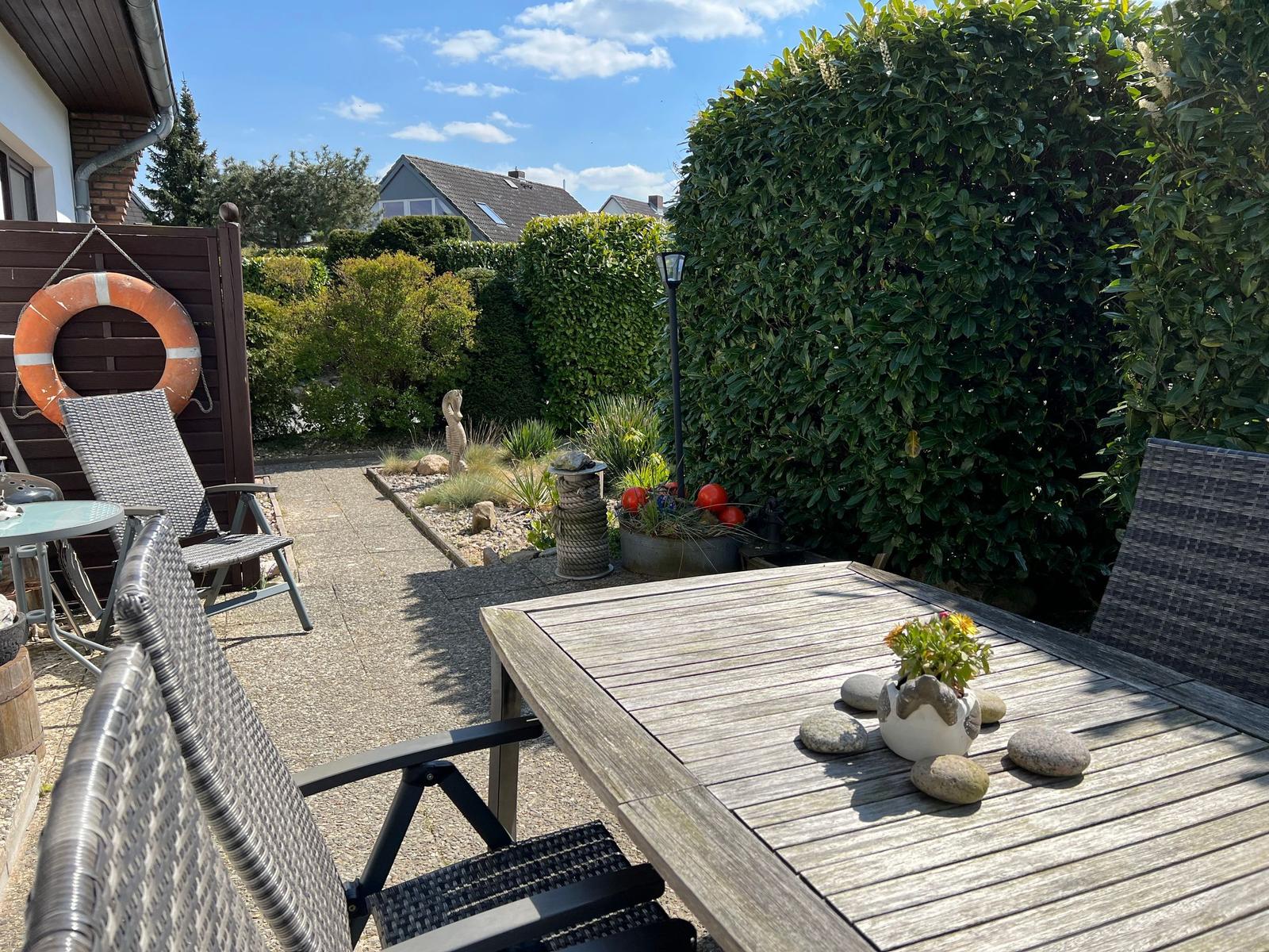 Ein Haus mit Dachgaube und Gartenweg zwischen grünen Hecken.