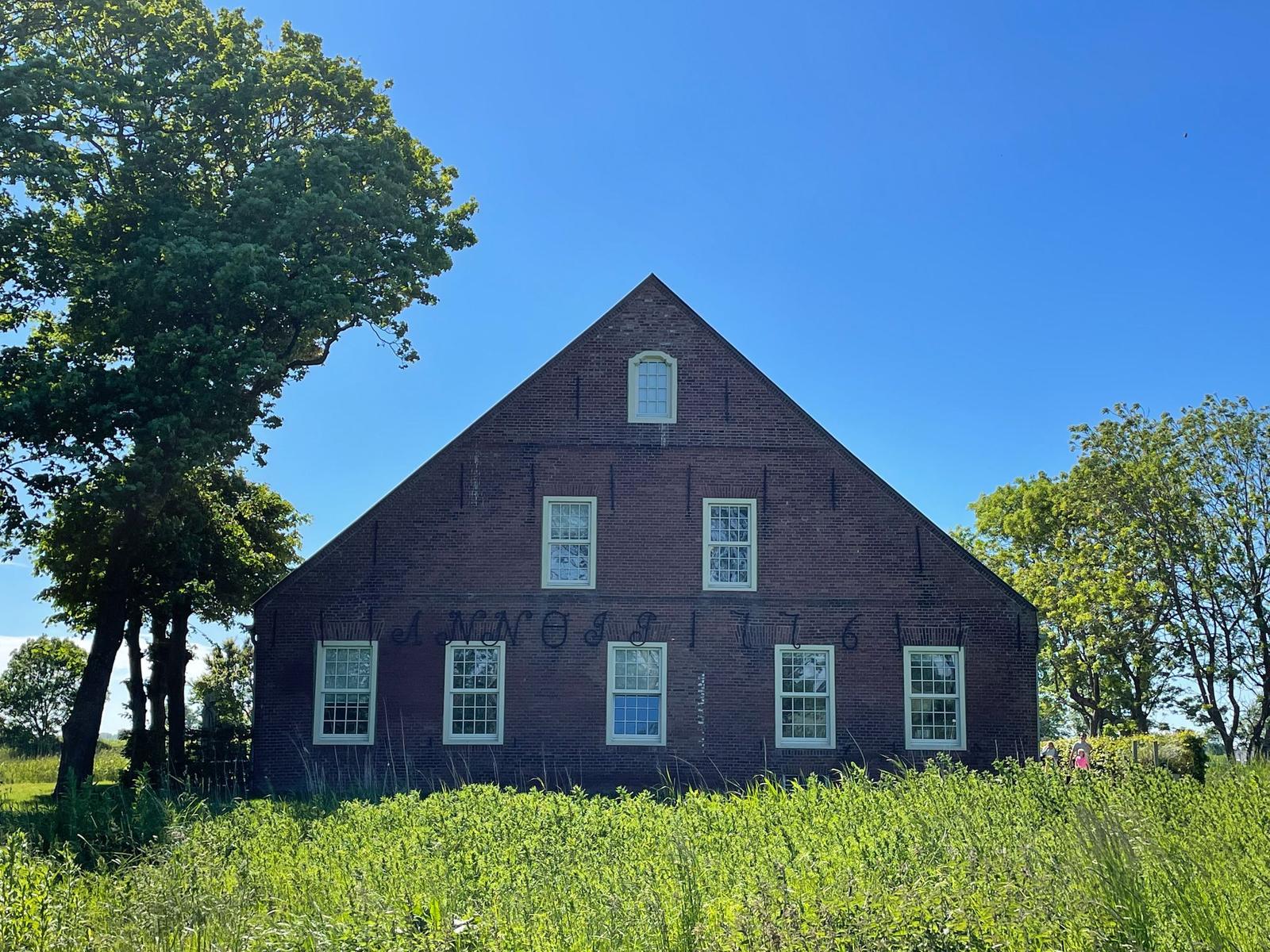 Ein großes Haus mit rotem Dach und grünem Garten unter blauem Himmel.