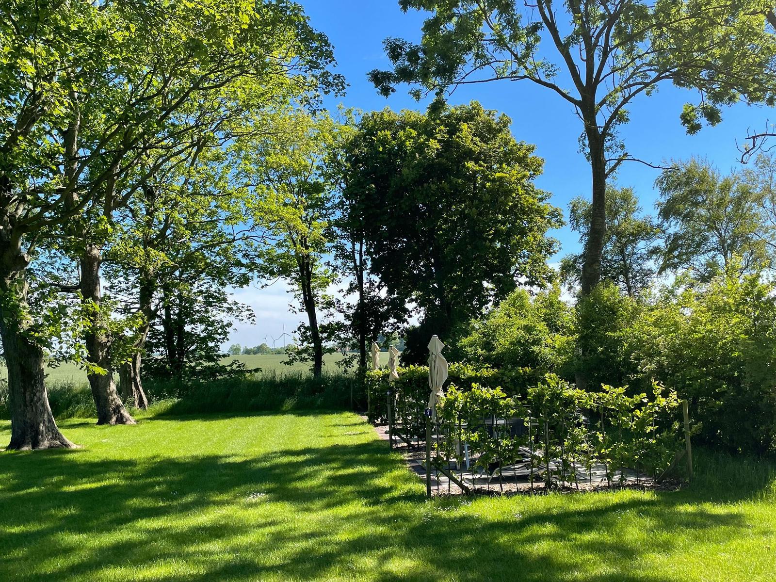 Haus mit Dach und Fenstern in grüner Landschaft unter blauem Himmel mit Sonne.