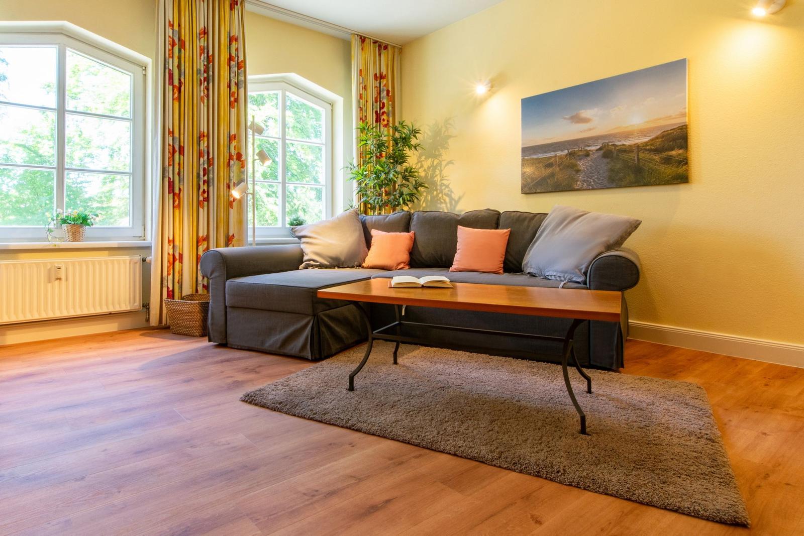 Esszimmer mit Holztisch, Stühlen und Gardinen vor Fenstern.