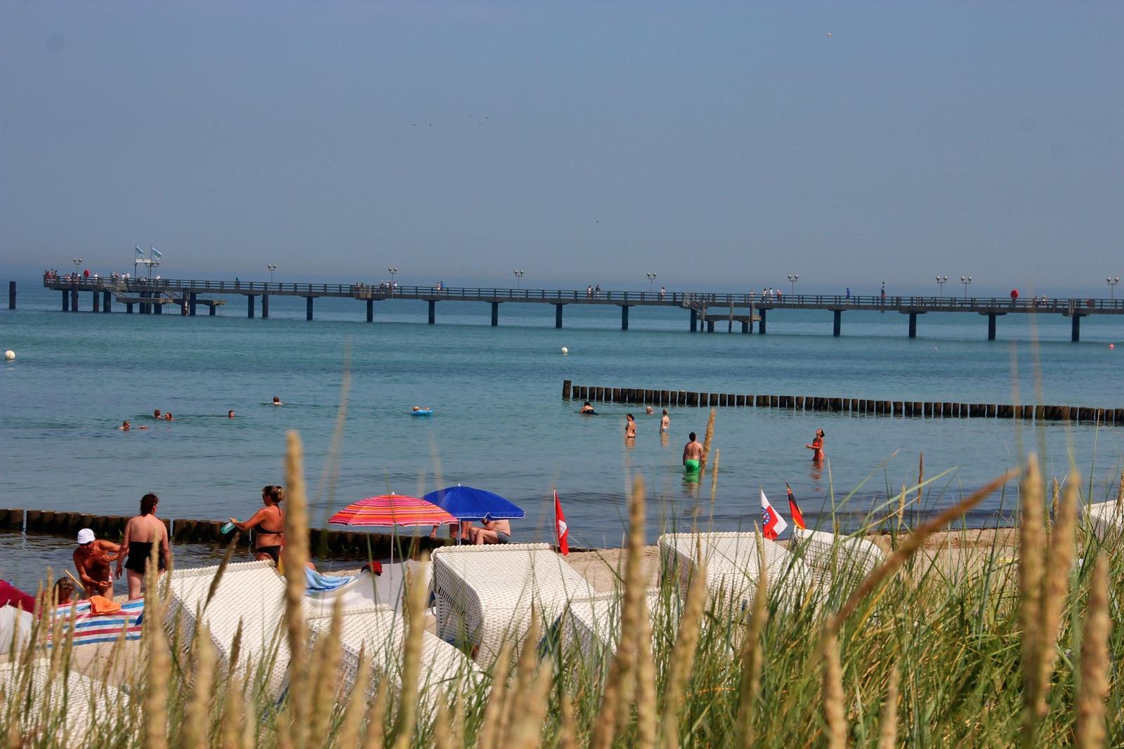 Eine große Menschenmenge beobachtet ein Feuerwerk am Strand bei Dämmerung.