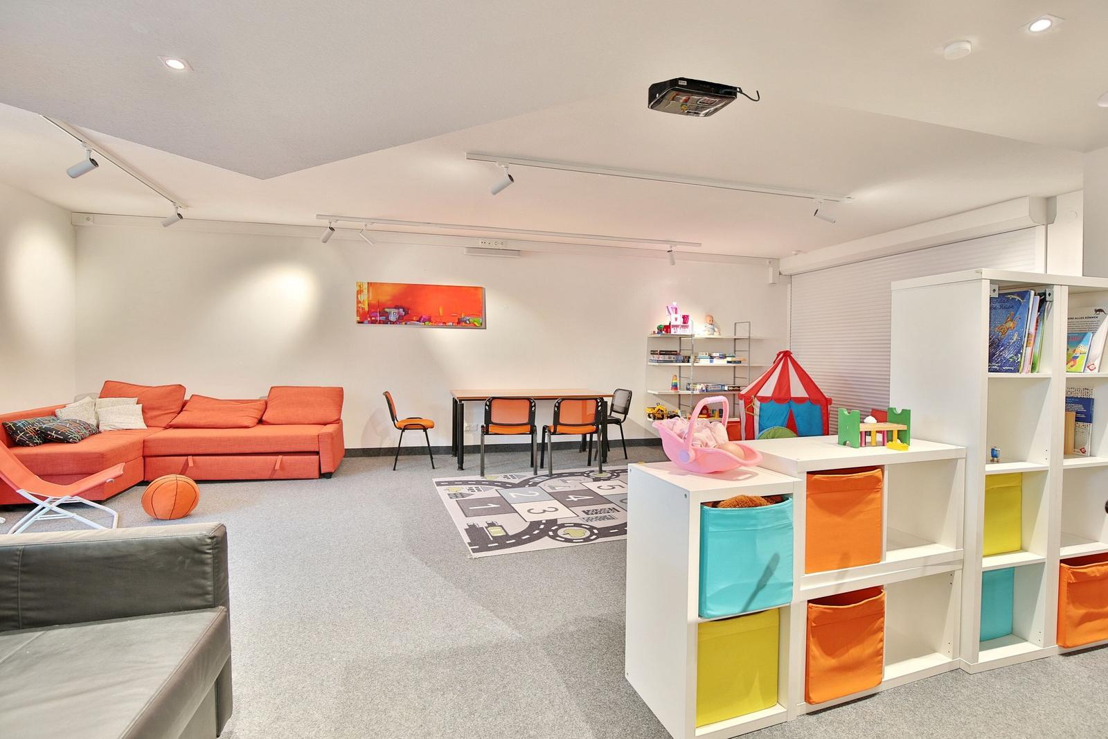Large room with sofa, colorful storage bins, and childrens area with table and chairs.