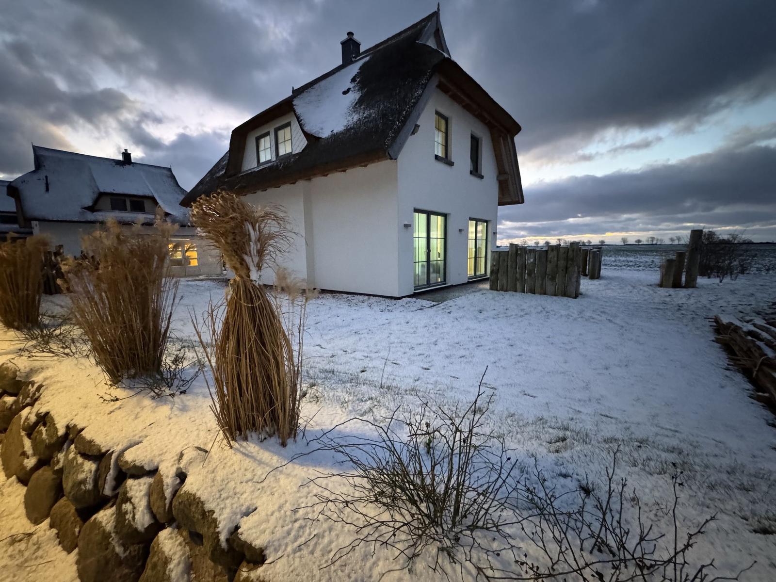 Wohnhaus mit Schneebedecktem Dach und großen Fenstern im Winter.
