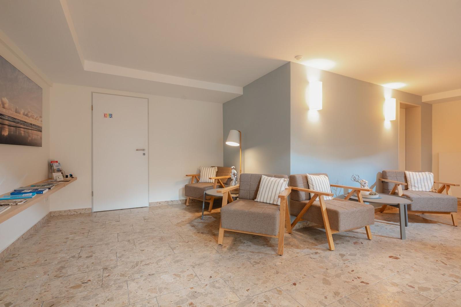 Raum mit drei Liegestühlen, Holzboden und Wandbild. Tür und Fenster sichtbar.