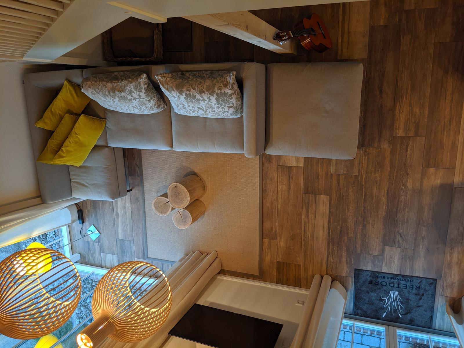 Holztisch mit Badematten, Eimer und Steinchen vor Fenster mit Rollladen.