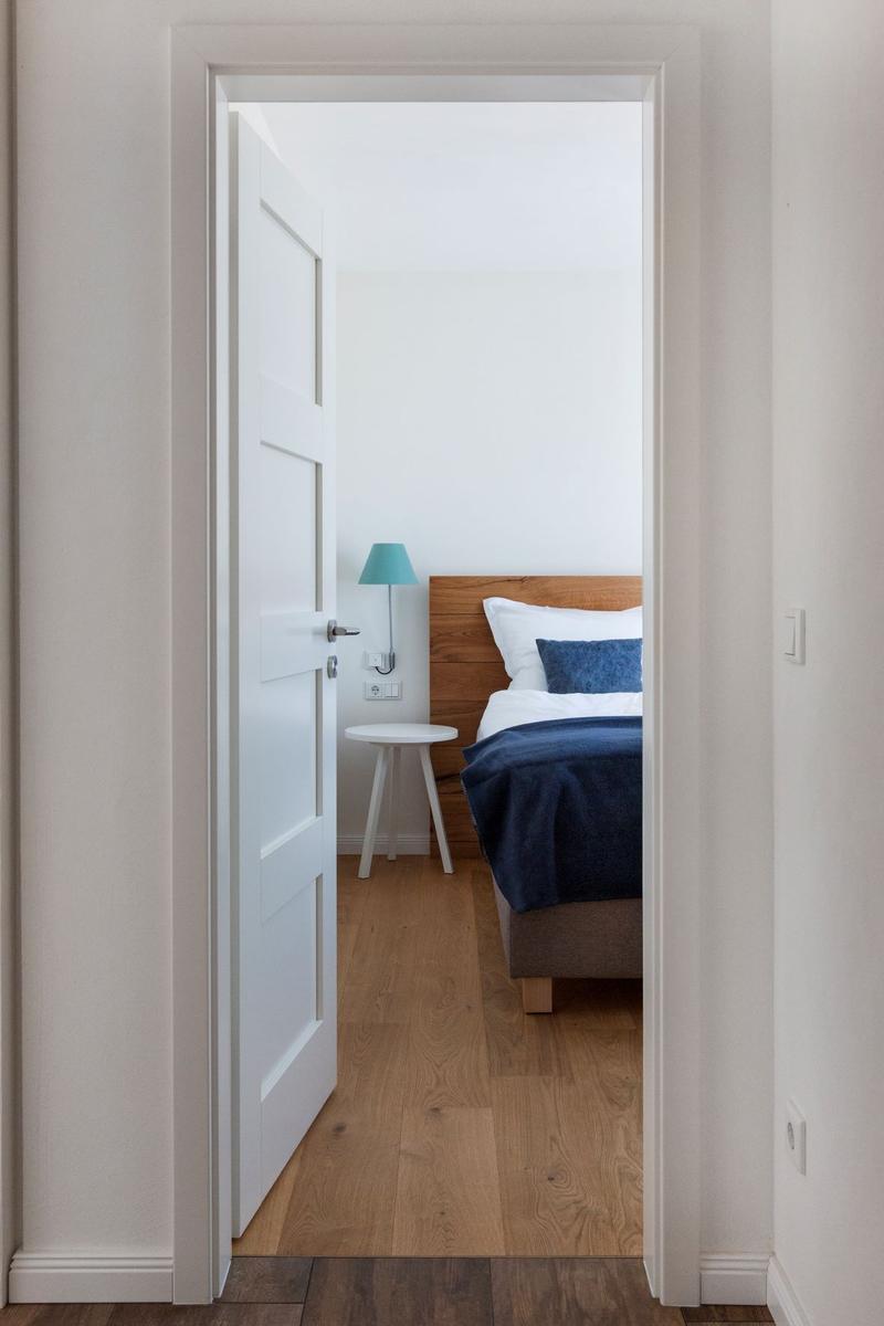 Bad mit runden Badewanne, gefliesten Wänden und Holzregal mit Handtüchern.