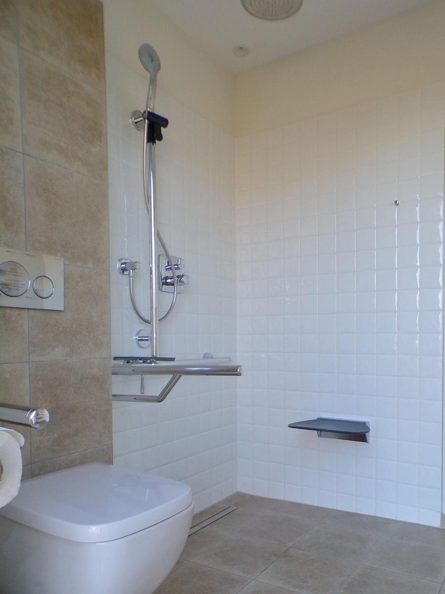 Saunaraum mit Holztür, Badewanne und Fenster mit Rollladen.