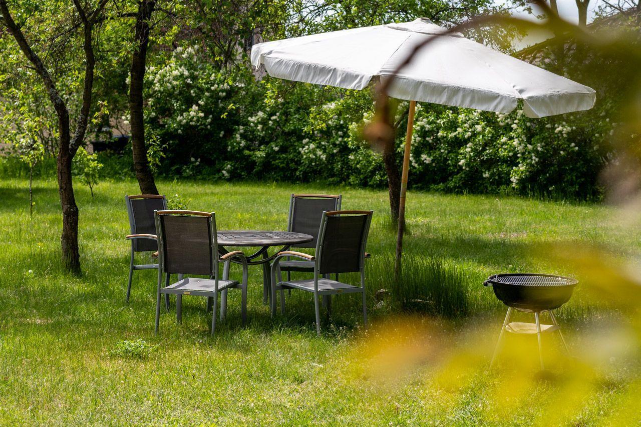 Two lounge chairs with checkered cushions are in the garden in front of a brick wall.