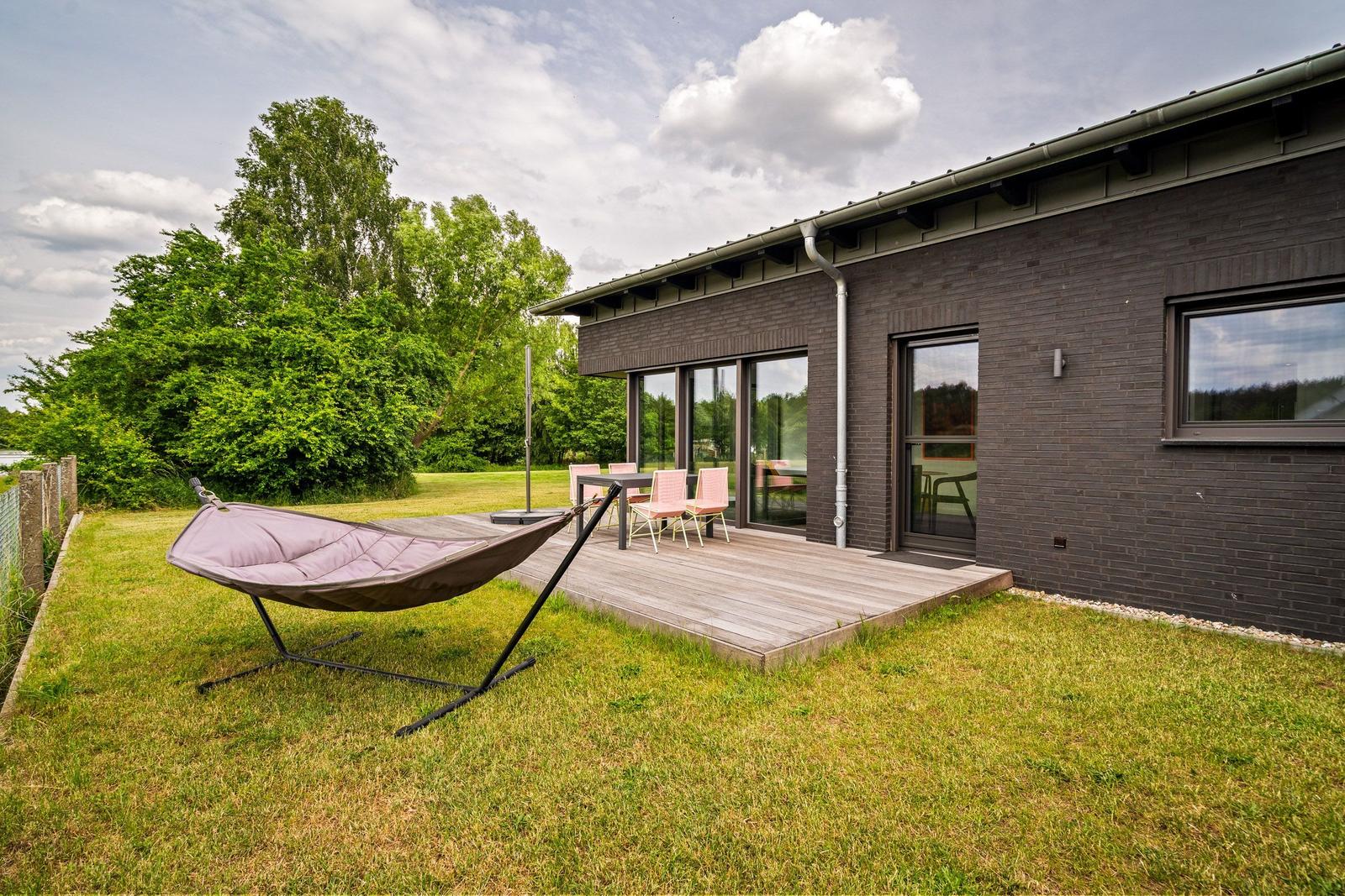 Moderne Villa mit großem Garten und Terrasse unter bewölktem Himmel.