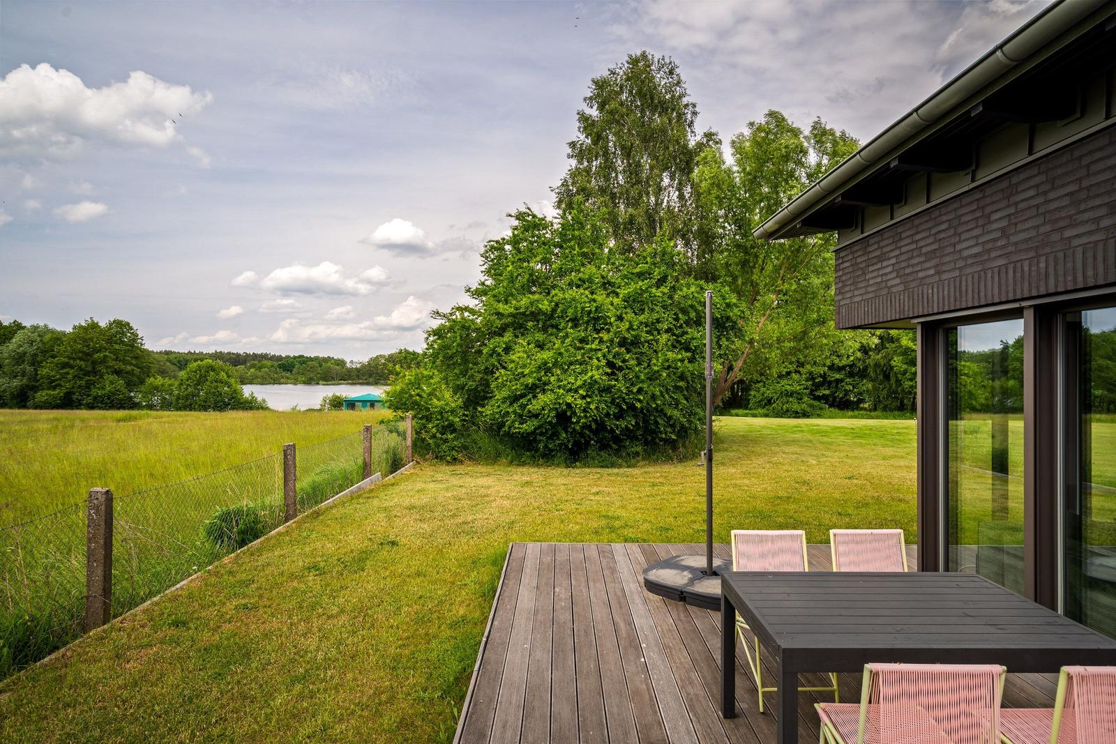 Moderne Villa mit Garten und Garage unter bewölktem Himmel.