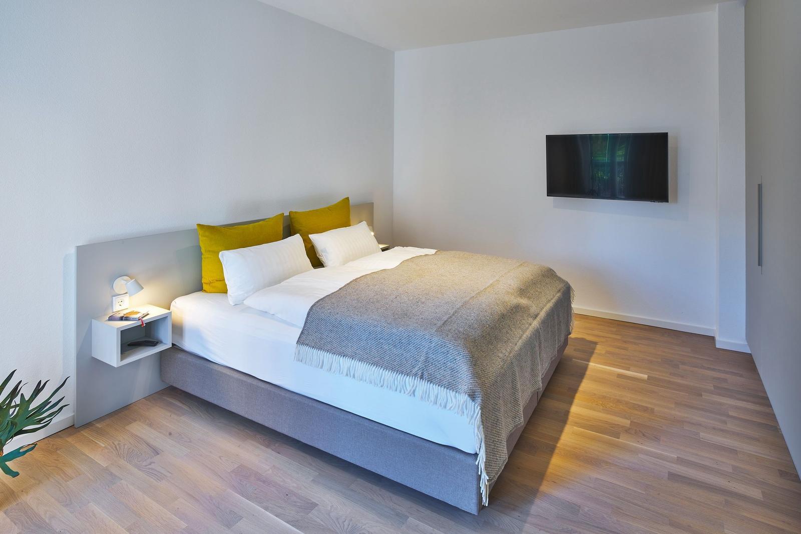 Schlafzimmer mit Bett, Kleiderschrank und Wand-TV.