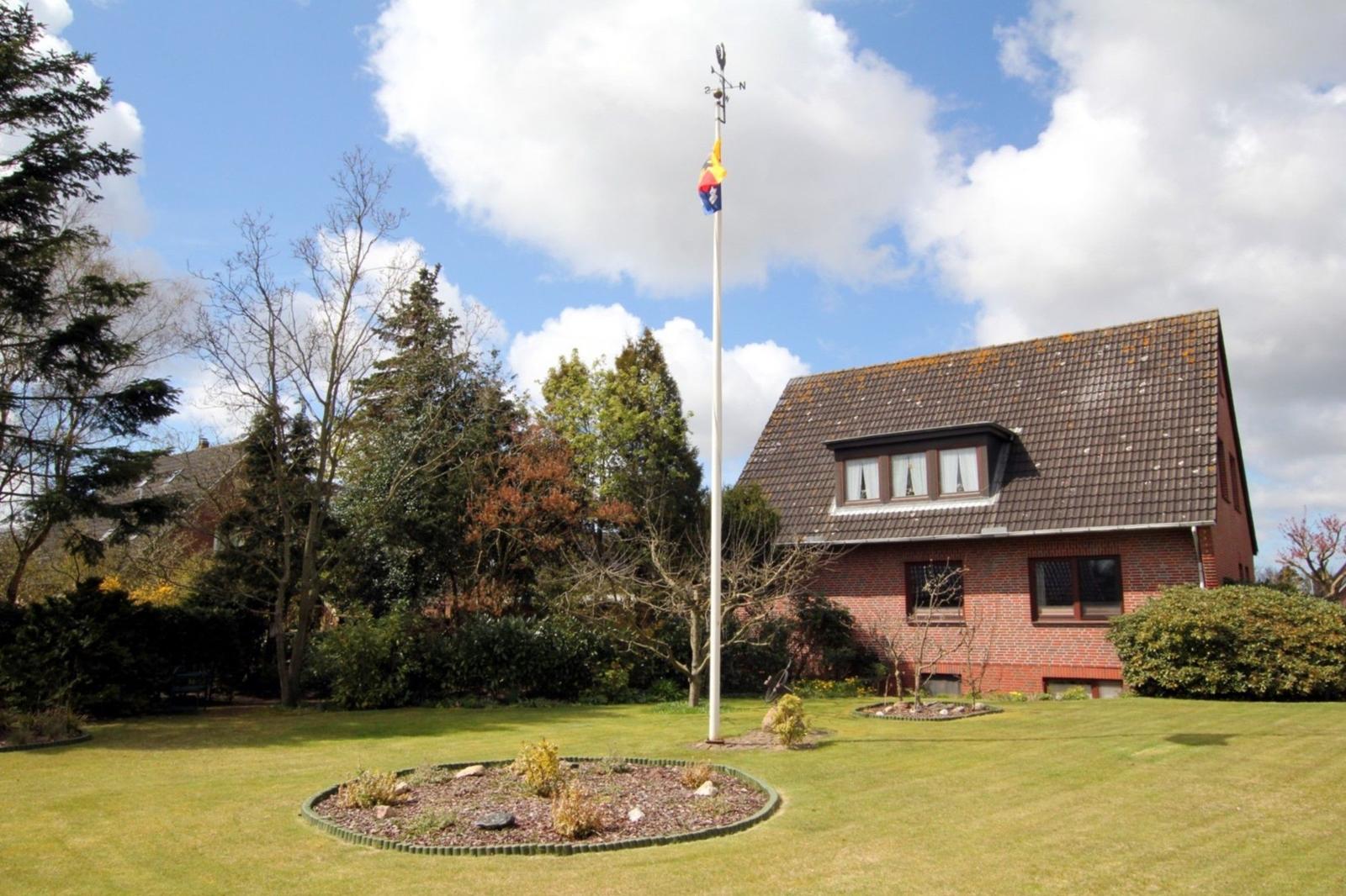 Hinterhof mit Spielplatz, Schaukel und Grillplatz. Grasfläche und Bäume umgeben den Bereich.