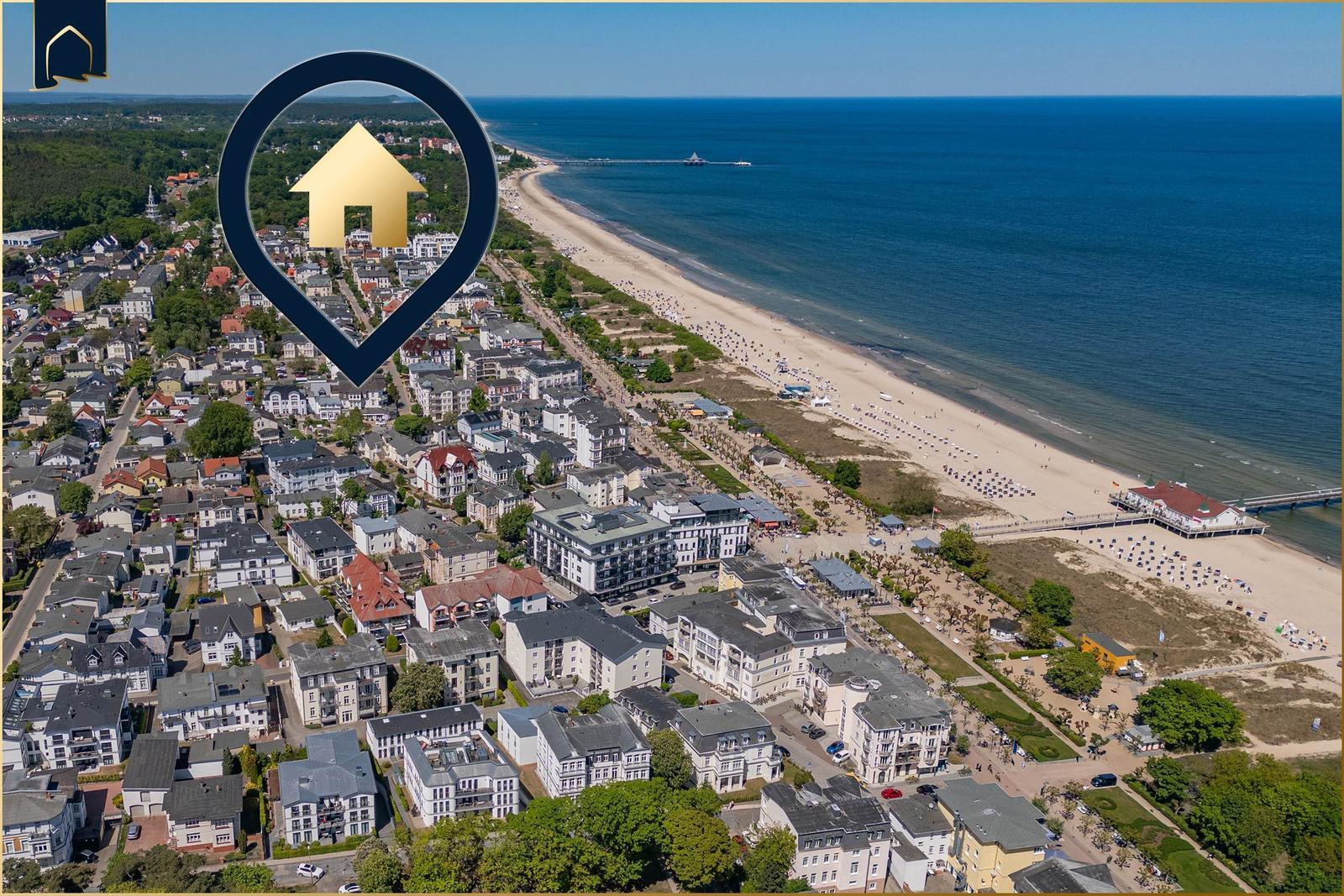 Aerial view of a coastal town with beach, sea, and residential buildings.