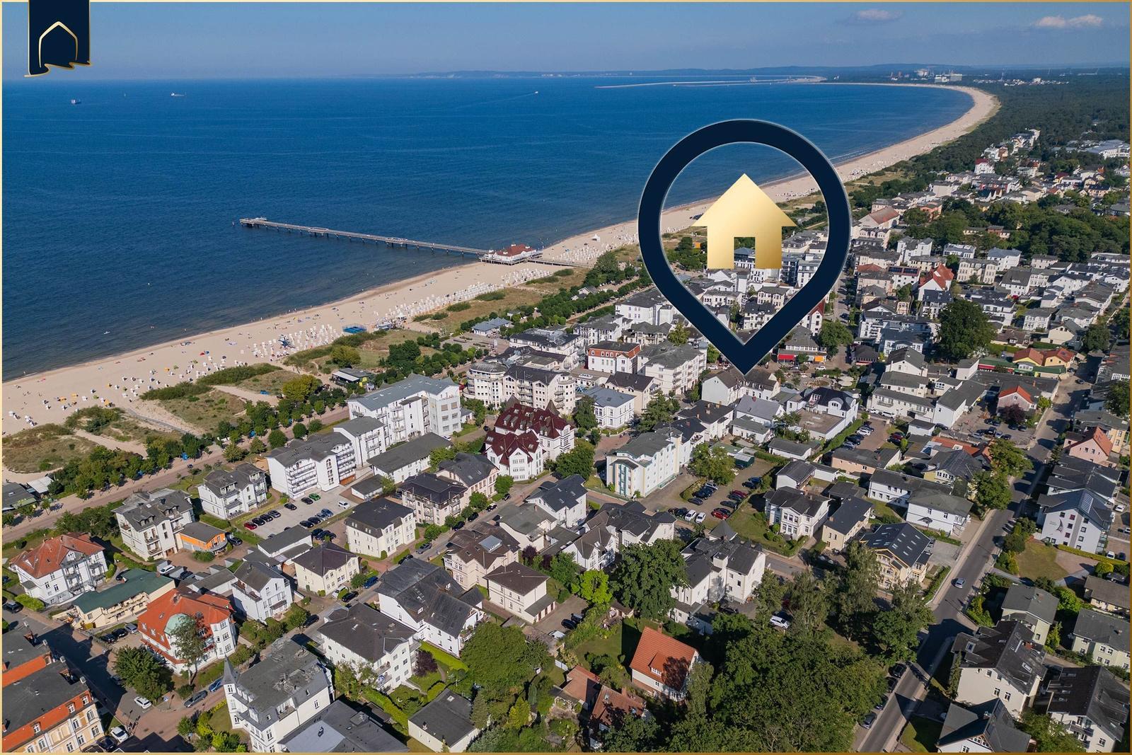 Sandpfad führt durch Gräser zur Strandpromenade bei Sonnenuntergang.
