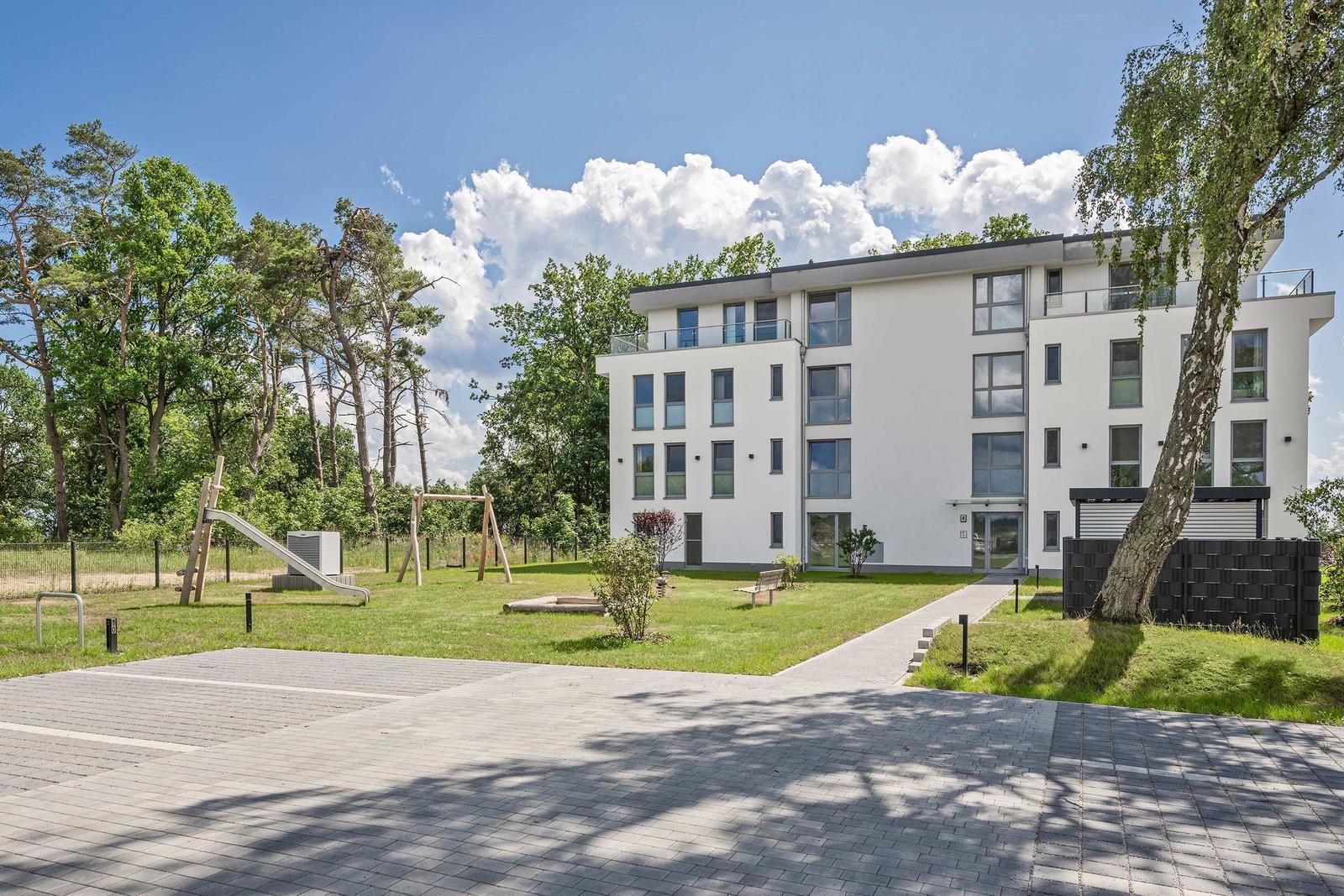 Holzbank und Tisch auf Steinplatten mit Blick auf See und Bäume.