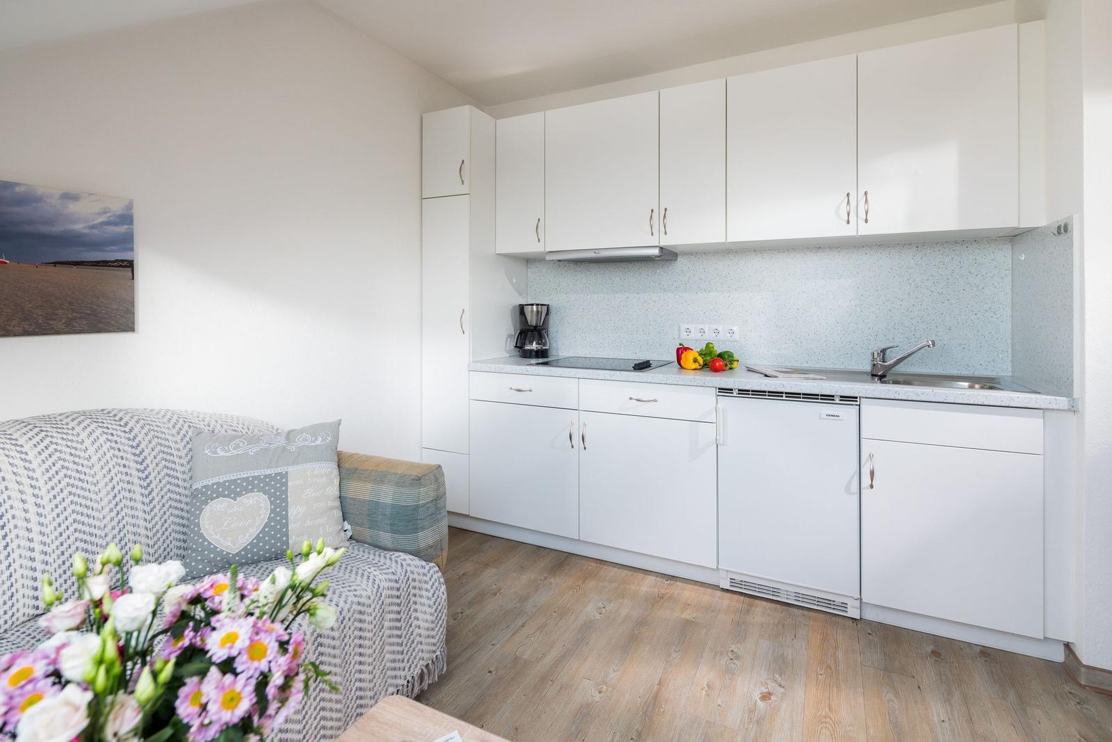 Wohnung mit Küche, Schlafzimmer und Bad. Holzboden und moderne Einrichtung.