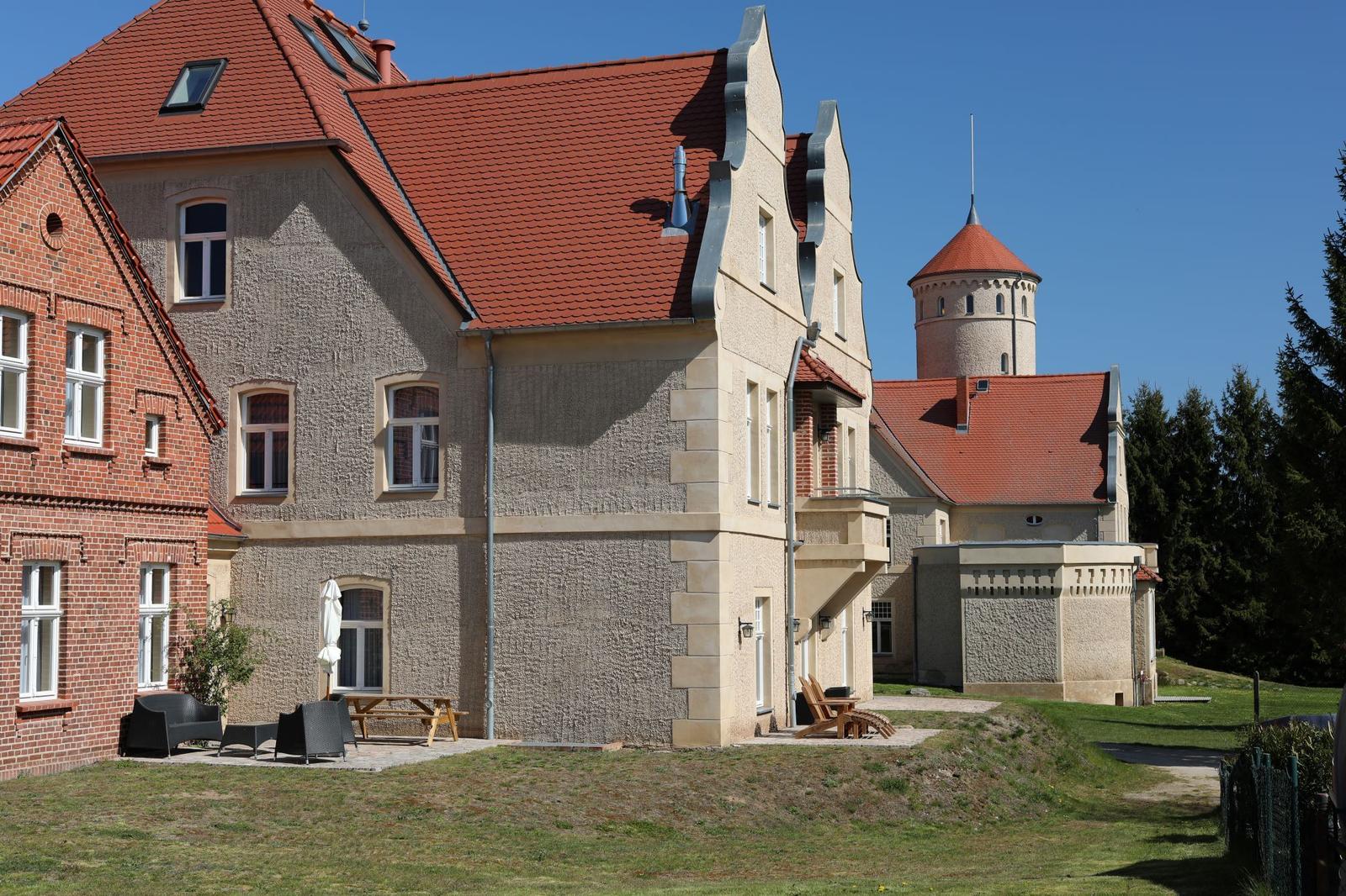Haus mit rotem Dach und Booten am Wasser.