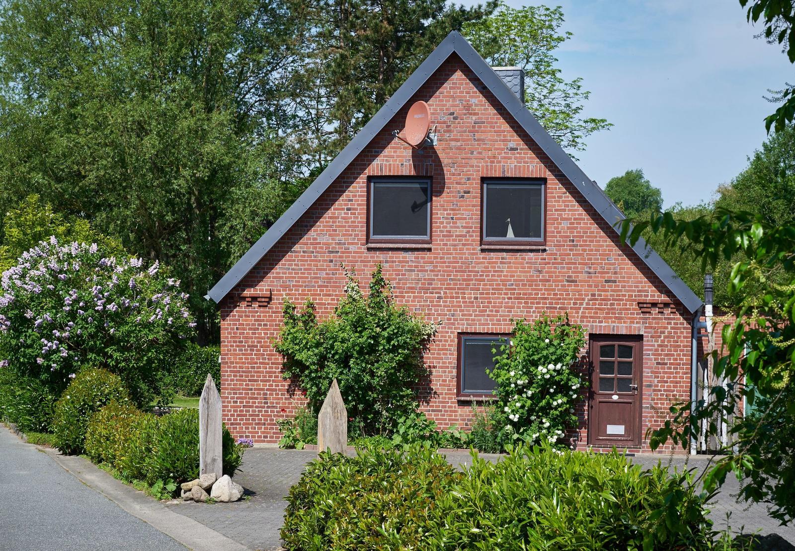 Red brick house with solar panels, balcony, and garden area.
