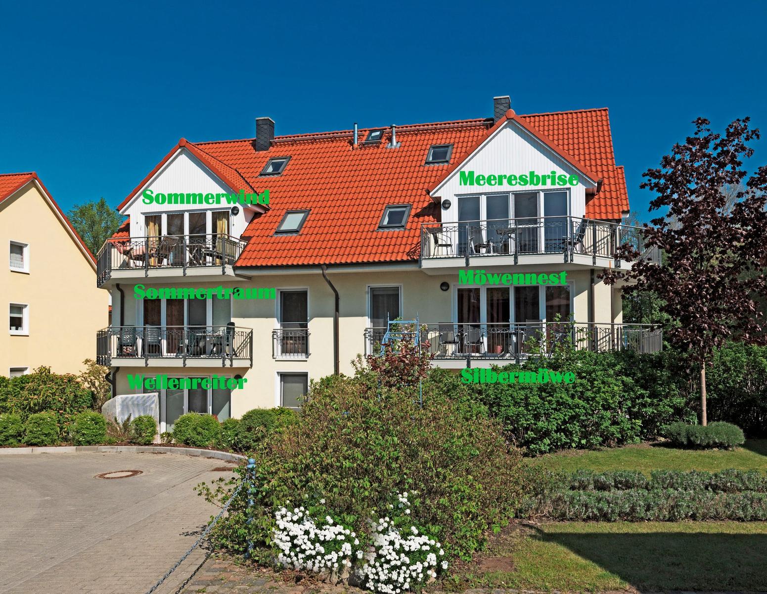 Strand mit Dünengras und Wellen unter blauem Himmel mit Wolken.