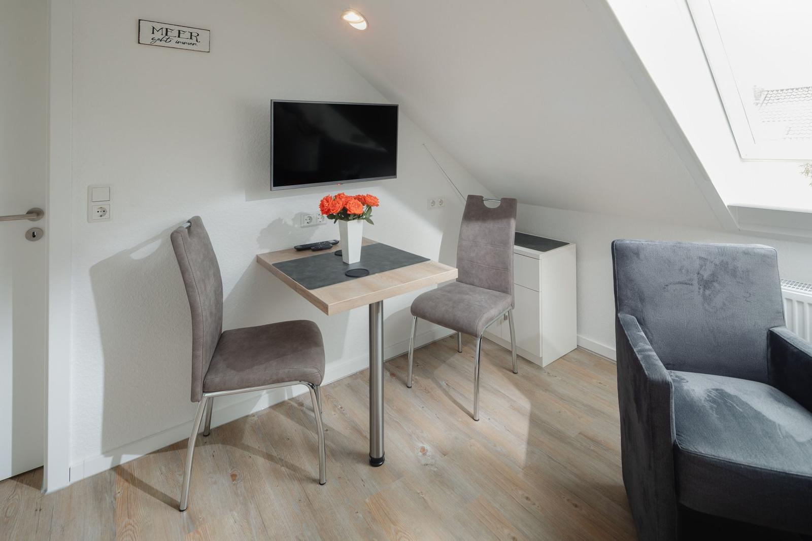 Schlafzimmer mit Doppelbett, TV und Kleiderschrank. Holzboden und Wandbild.