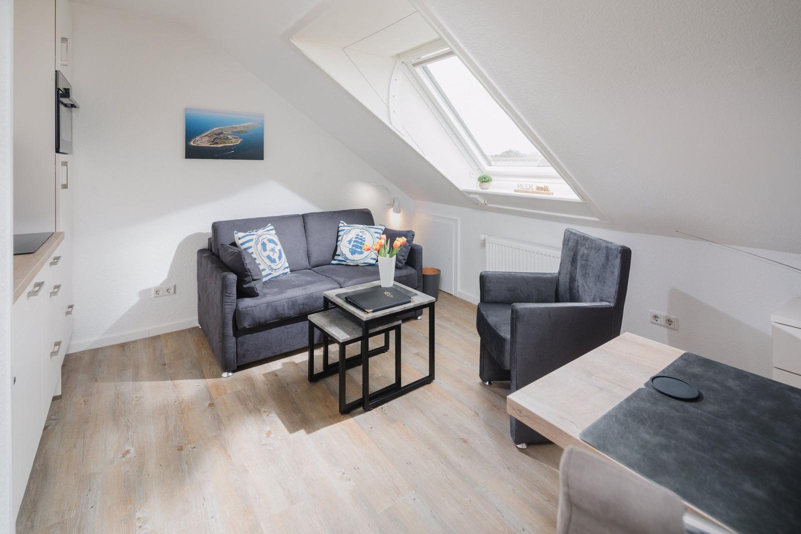 Dachgeschosszimmer mit Esstisch, Fernseher und Sitzgelegenheit.