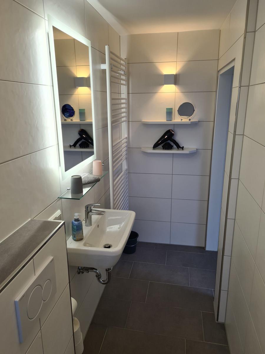 Ein Schlafzimmer mit Bett, Küche mit Kochfeld und Waschbecken, sowie Wohnbereich mit Sofa.
