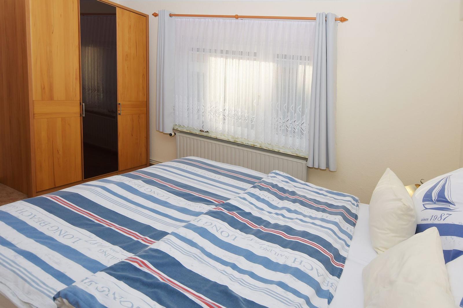 Ein Wohnzimmer mit blauem Sofa, beigem Sessel und Holzboden.