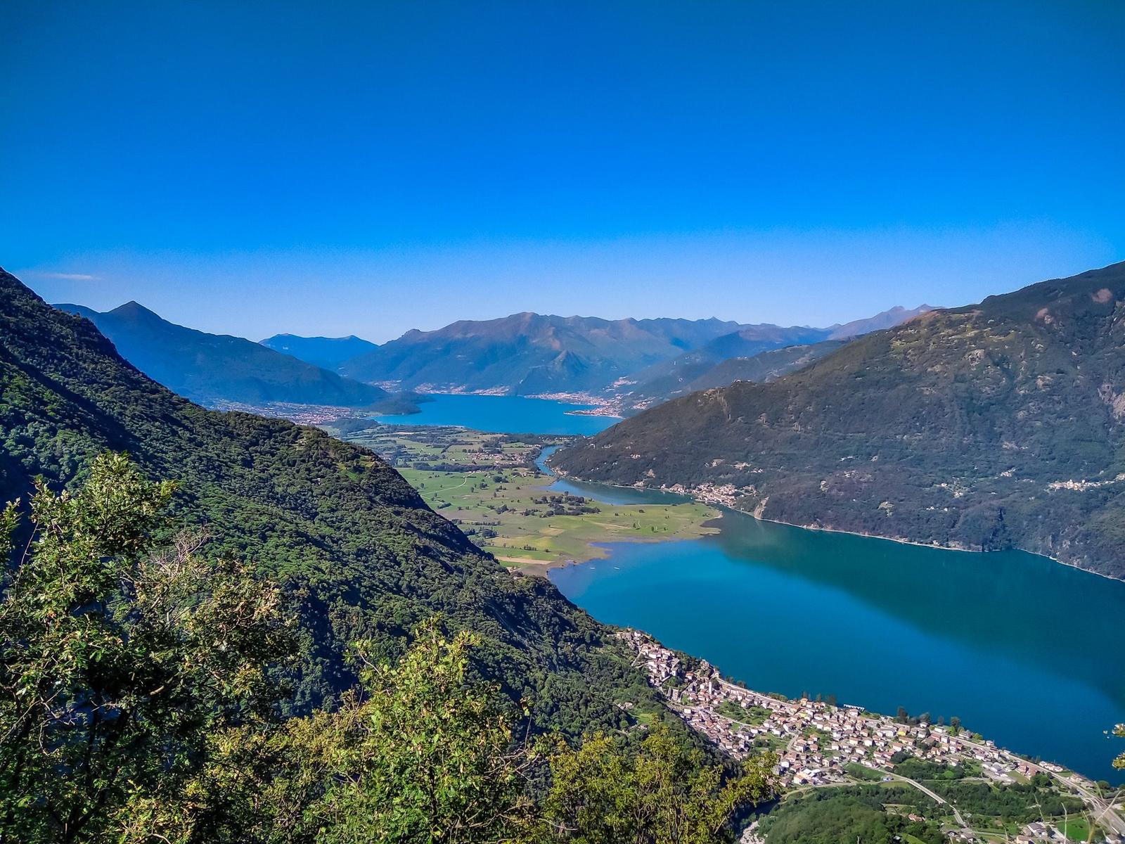 Grüner Hang mit Liegen und Sonnenschirmen vor Berglandschaft
