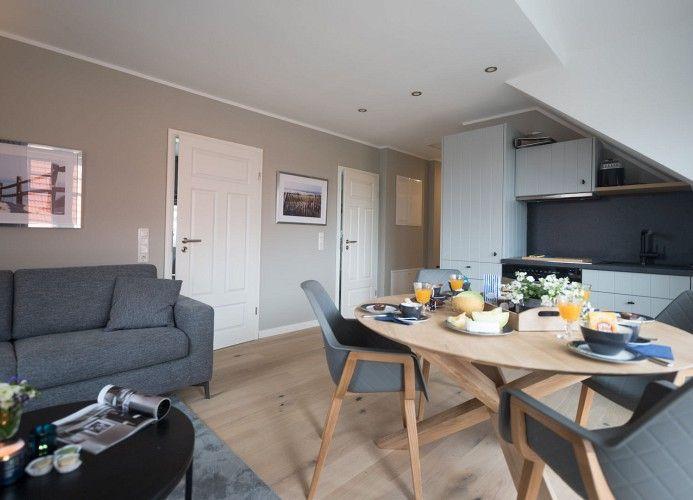 Rundes Esstisch mit Frühstück, Sofa, TV und Blick in Schlafzimmer.