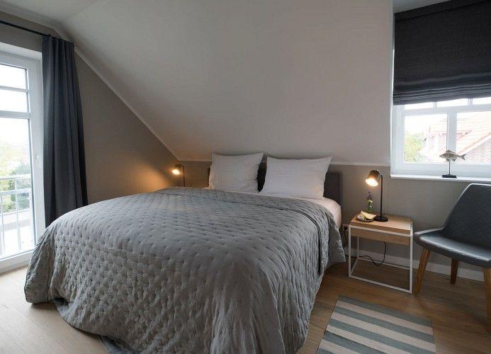 Schlafzimmer mit Dachschrägen, Bett, Kleiderschrank und Spiegel.