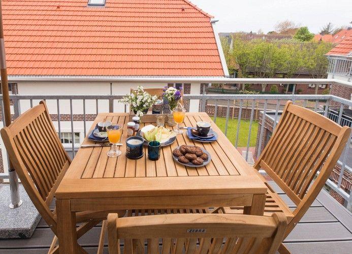 Auf dem Tisch stehen Blumen, eine Kerze, Magazine und Gebäck.