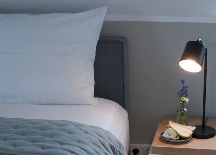 Ein Schlafzimmer mit Dachschräge, Bett, Stuhl und kleinem Tisch.