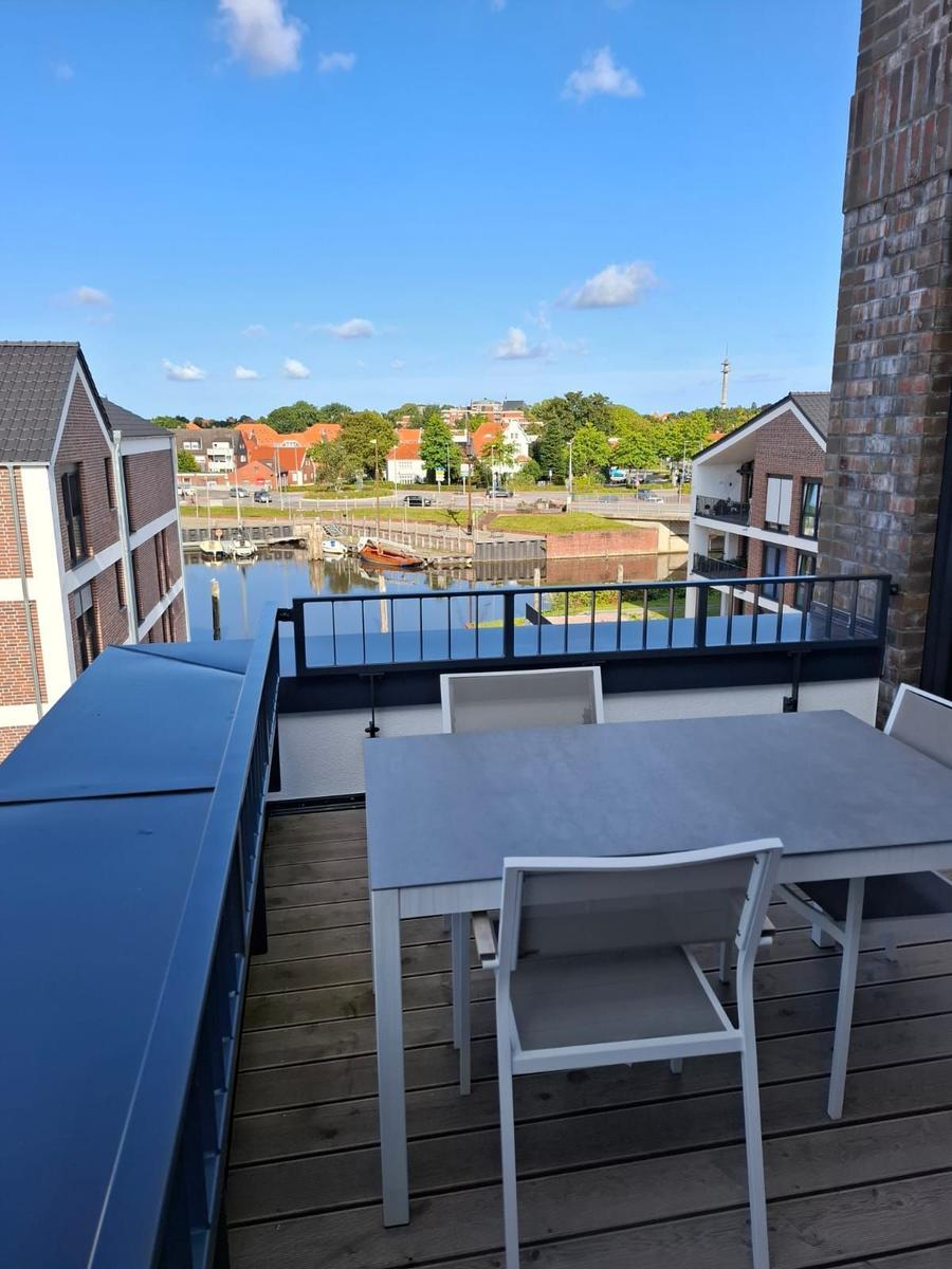 Terrasse mit Blick auf Hafen und Gebäude unter blauem Himmel.
