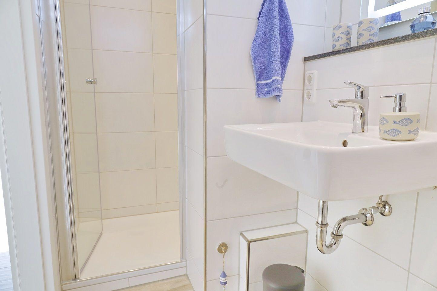 Badezimmer mit Dusche, Waschbecken und Handtuchhalter