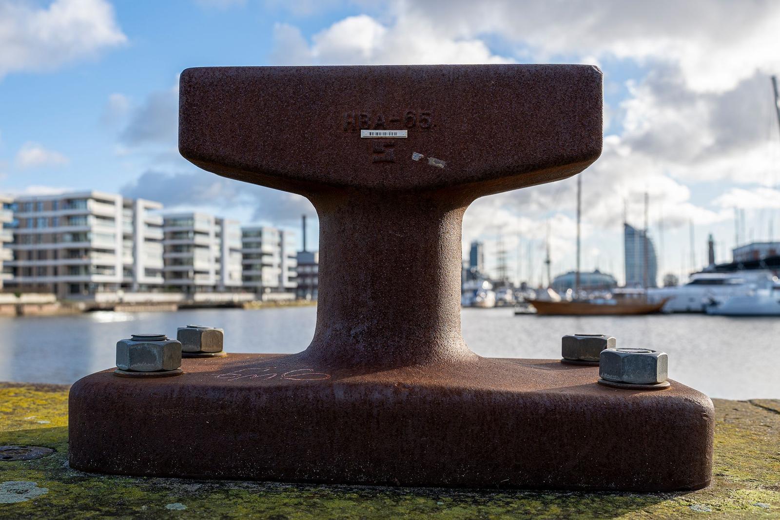 Hafen mit Booten und Spiegelung im Wasser unter bewölktem Himmel.
