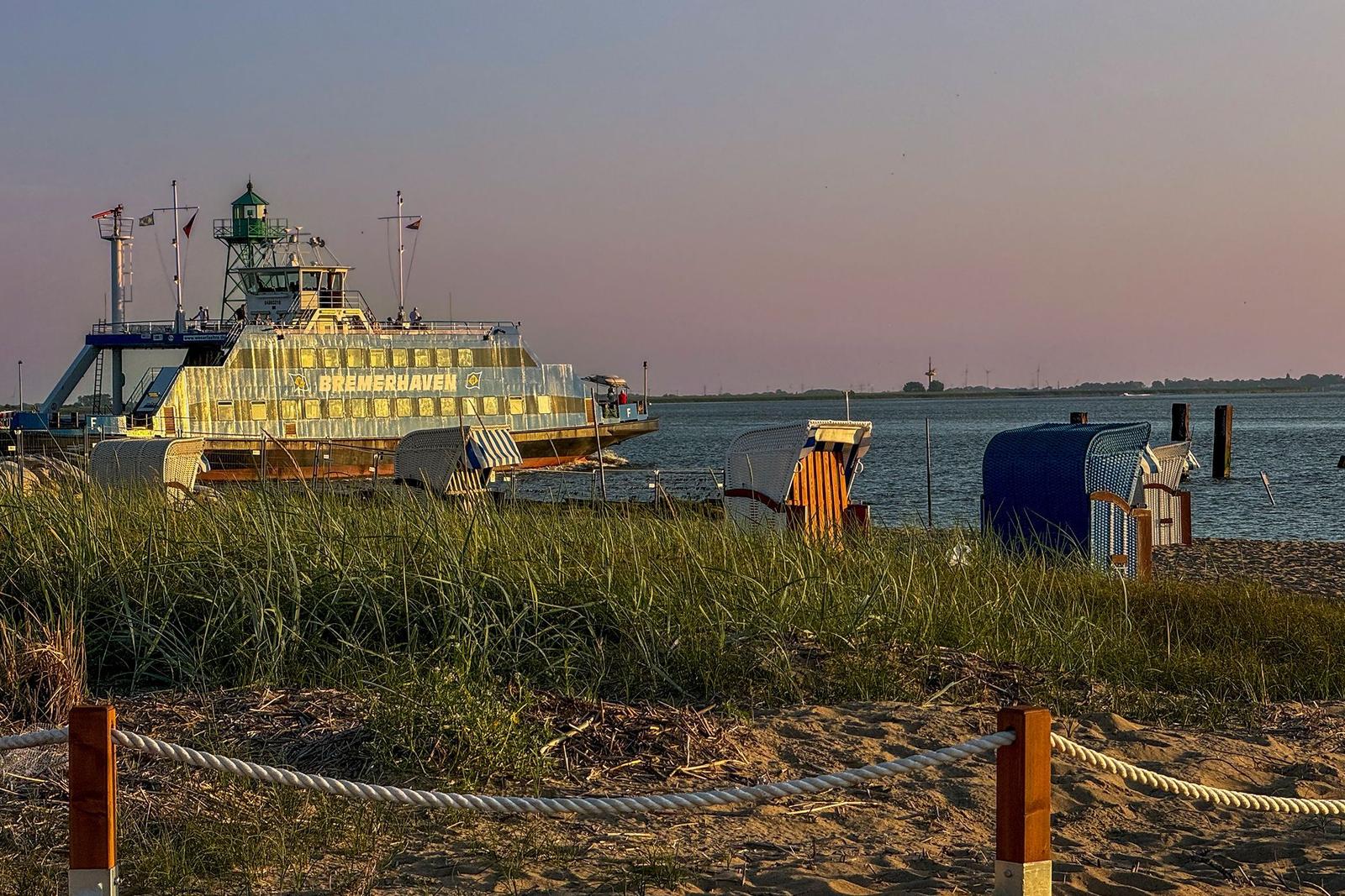 Sonnenuntergang am Strand mit Blick auf moderne Gebäude und Watt.