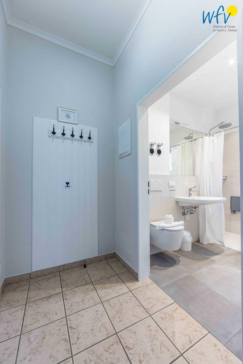 Flur mit Garderobe und Blick in die Toilette und Dusche.