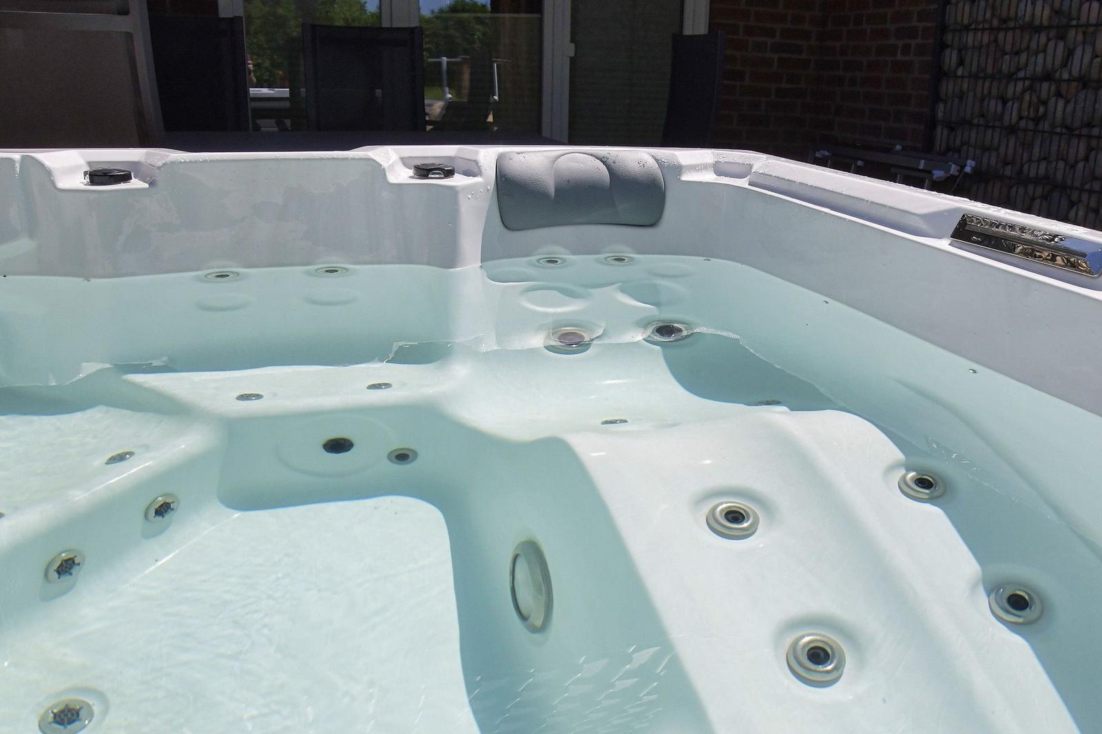 Ein weißer Whirlpool mit mehreren Massagehöhlen und einem Kopfstützenbereich.